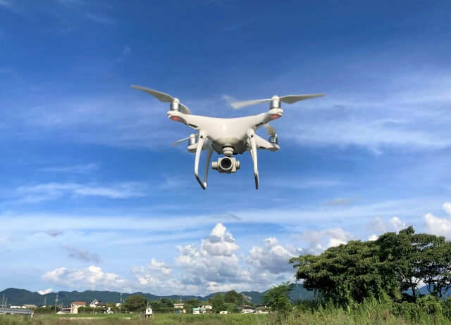 晴天の空を飛ぶ白いドローン